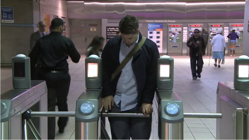 Man going through turn style at train station